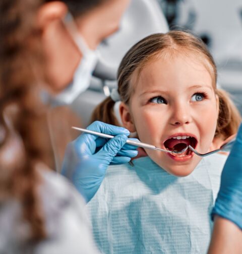 Laps istub hambaravi toolis ja naeratab