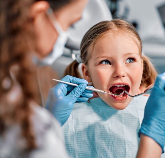 Laps istub hambaravi toolis ja naeratab